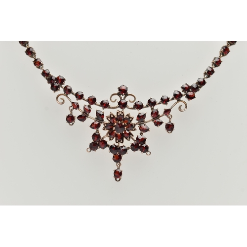 135 - A BOHEMIAN GARNET FESTOON STYLE NECKLACE, rose metal set with a cluster of circular cut garnets, lea... 