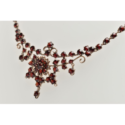 135 - A BOHEMIAN GARNET FESTOON STYLE NECKLACE, rose metal set with a cluster of circular cut garnets, lea... 