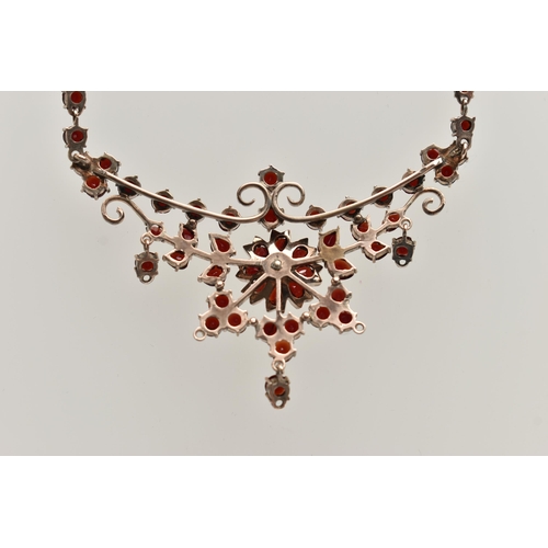 135 - A BOHEMIAN GARNET FESTOON STYLE NECKLACE, rose metal set with a cluster of circular cut garnets, lea... 