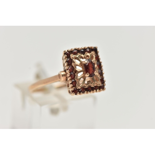 47 - A 9CT GOLD GARNET DRESS RING, rectangular form, set with a principle oval cut garnet and eighteen ci... 