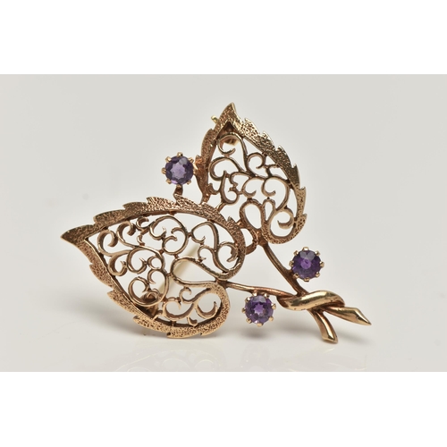 17 - A 9CT GOLD, AMETHYST BROOCH, in the form of two open work leaves, set with three circular cut amethy... 