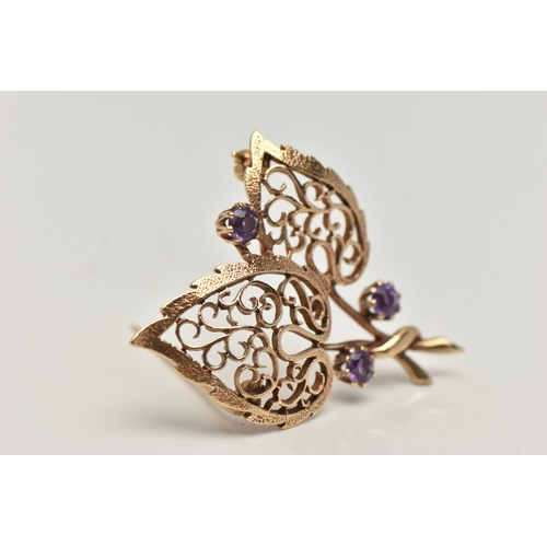 17 - A 9CT GOLD, AMETHYST BROOCH, in the form of two open work leaves, set with three circular cut amethy... 