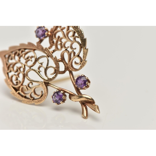 17 - A 9CT GOLD, AMETHYST BROOCH, in the form of two open work leaves, set with three circular cut amethy... 