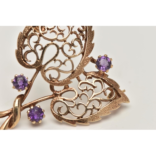 17 - A 9CT GOLD, AMETHYST BROOCH, in the form of two open work leaves, set with three circular cut amethy... 