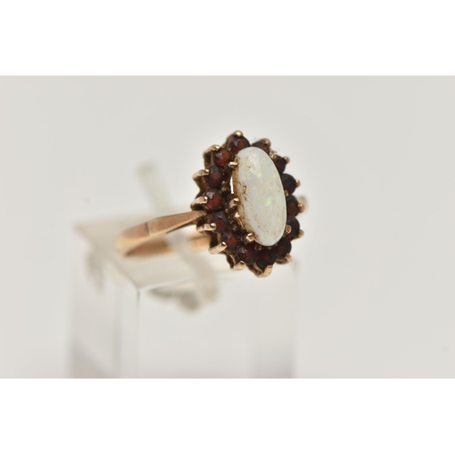 29 - A 9CT GOLD CLUSTER RING, of an oval form, set with a central opal cabochon, in a surround of circula... 