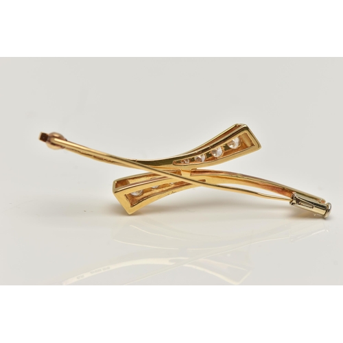 7 - AN 18CT GOLD DIAMOND BROOCH, cross over style bar brooch, set with two rows of graduated round brill... 