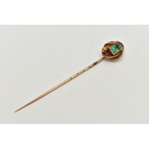 114 - A YELLOW METAL EMERALD AND COILED SNAKE STICK PIN, centring on an emerald cut emerald, in a claw set... 