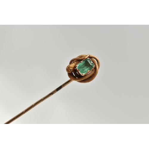 114 - A YELLOW METAL EMERALD AND COILED SNAKE STICK PIN, centring on an emerald cut emerald, in a claw set... 