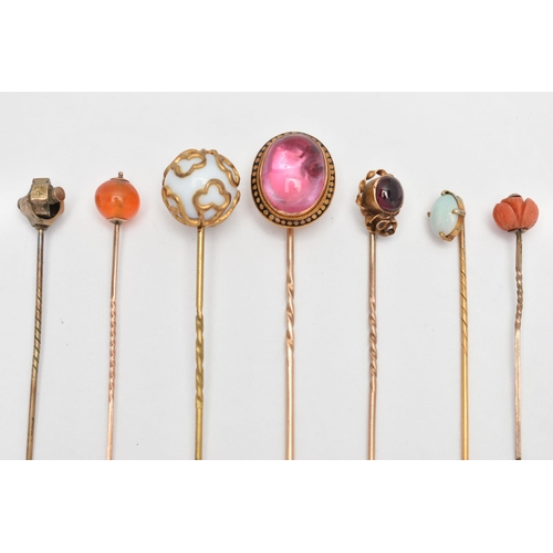 115 - SEVEN YELLOW METAL STICK PINS, to include a pink foiled back paste cabochon in a yellow metal and bl... 