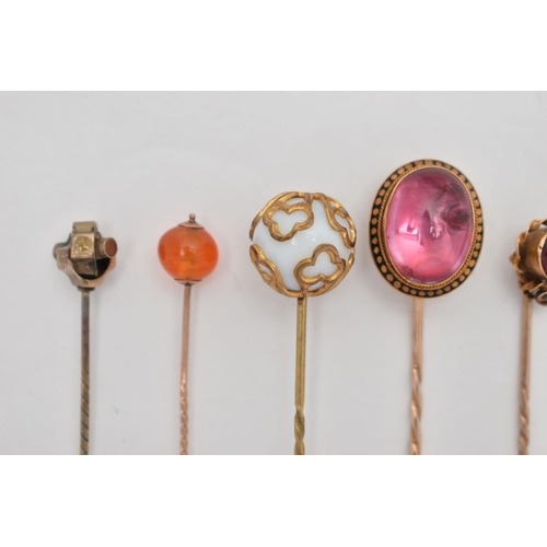 115 - SEVEN YELLOW METAL STICK PINS, to include a pink foiled back paste cabochon in a yellow metal and bl... 