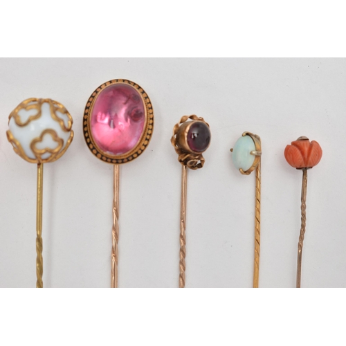 115 - SEVEN YELLOW METAL STICK PINS, to include a pink foiled back paste cabochon in a yellow metal and bl... 