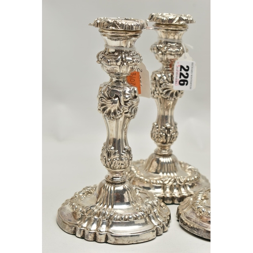 226 - A SET OF FOUR GEORGE IV SILVER CANDLESTICKS, circular form with foliage and scrolling detail to the ... 