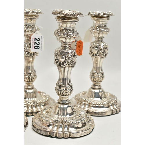 226 - A SET OF FOUR GEORGE IV SILVER CANDLESTICKS, circular form with foliage and scrolling detail to the ... 