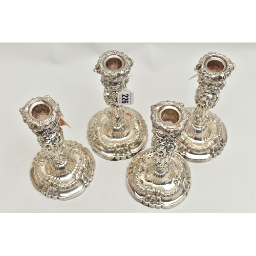 226 - A SET OF FOUR GEORGE IV SILVER CANDLESTICKS, circular form with foliage and scrolling detail to the ... 