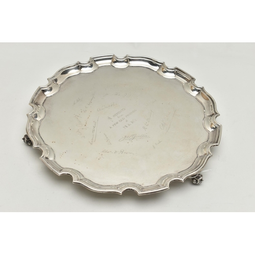 231 - AN EARLY 20TH CENTURY SILVER SALVER, circular form with wavy rim, raised on three scrolling feet, pe... 