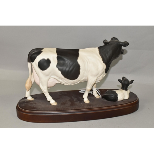 396 - A ROYAL DOULTON FRIESIAN COW AND CALF, standing on a wooden plinth, model no A2607/2690, height incl... 