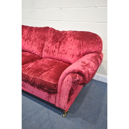 1304 - A RED VELVETEEN UPHOLSTERED TWO SEATER SETTEE, on turned legs and brass casters, length 202cm x dept... 