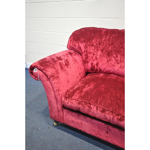 1304 - A RED VELVETEEN UPHOLSTERED TWO SEATER SETTEE, on turned legs and brass casters, length 202cm x dept... 