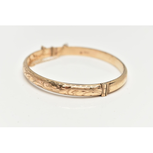 28 - A 9CT GOLD HINGED BANGLE, engraved floral pattern to the front, fitted with an integrated push piece... 