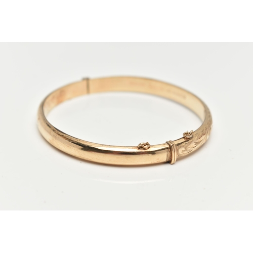 28 - A 9CT GOLD HINGED BANGLE, engraved floral pattern to the front, fitted with an integrated push piece... 