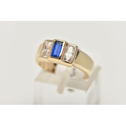 49 - A YELLOW METAL CUBIC ZIRCONIA RING, set with one blue and two colourless cubic zirconia stones, wide... 