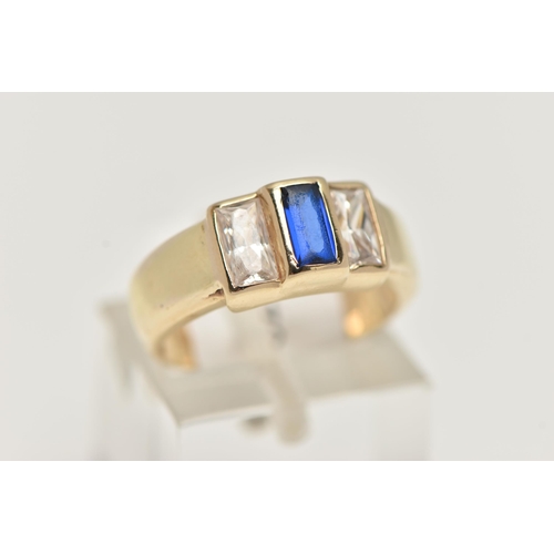 49 - A YELLOW METAL CUBIC ZIRCONIA RING, set with one blue and two colourless cubic zirconia stones, wide... 