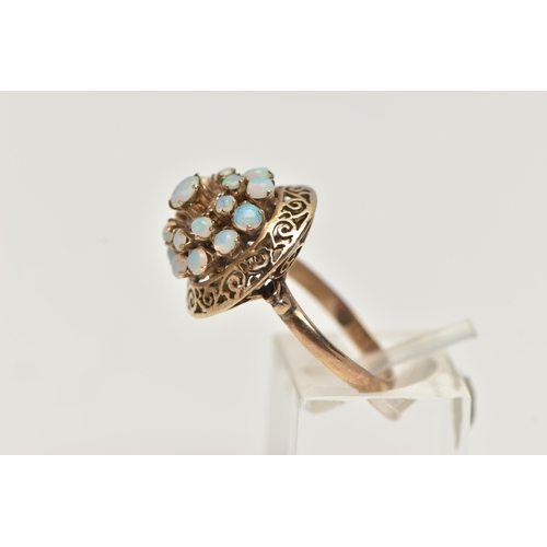 57 - A YELLOW METAL OPAL RING, tiered ring set with opal cabochons, to the openwork scroll surround, poli... 