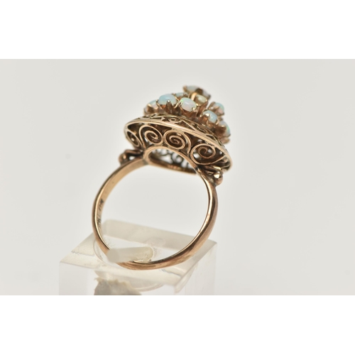 57 - A YELLOW METAL OPAL RING, tiered ring set with opal cabochons, to the openwork scroll surround, poli... 