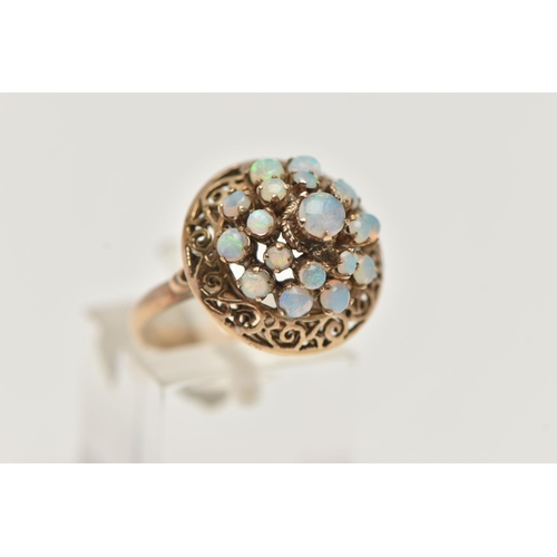 57 - A YELLOW METAL OPAL RING, tiered ring set with opal cabochons, to the openwork scroll surround, poli... 