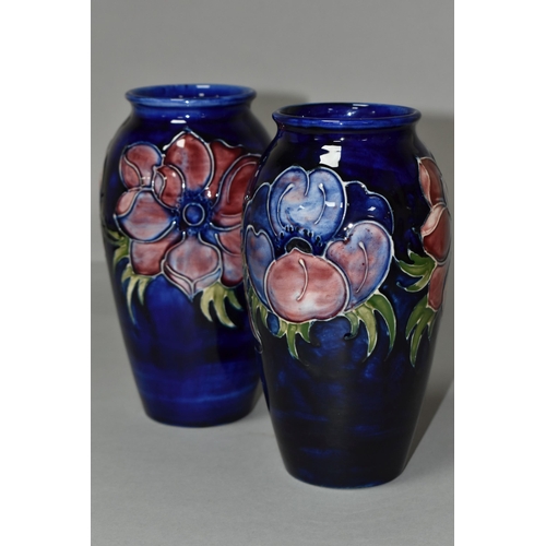 369 - TWO MOORCROFT VASES, purple and mauve anemone design on a dark blue ground, height 19cm, blue painte... 