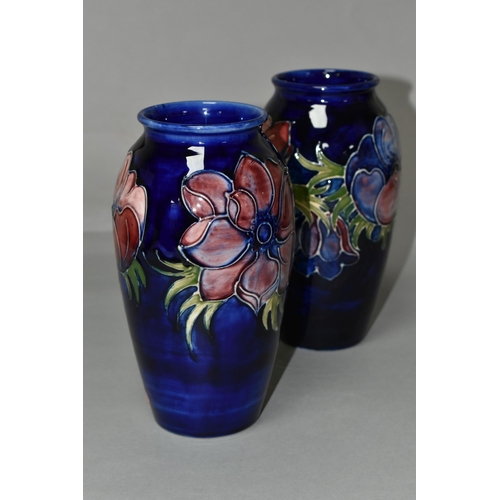 369 - TWO MOORCROFT VASES, purple and mauve anemone design on a dark blue ground, height 19cm, blue painte... 