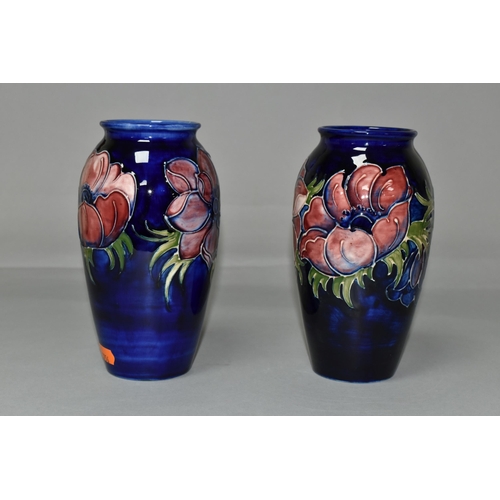 369 - TWO MOORCROFT VASES, purple and mauve anemone design on a dark blue ground, height 19cm, blue painte... 