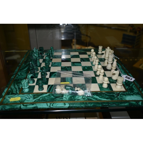 561 - A MALACHITE AND HARDSTONE CHESS SET, the 37cm square board inlaid with brass stringing, height of ki... 