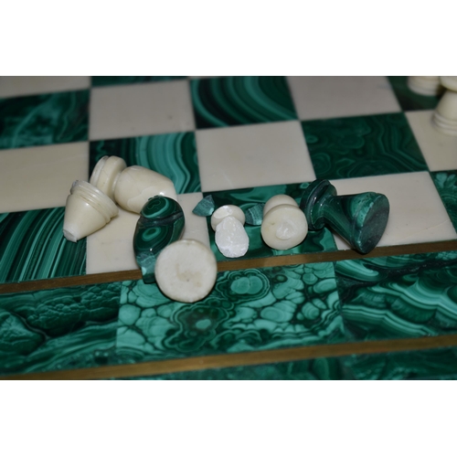 561 - A MALACHITE AND HARDSTONE CHESS SET, the 37cm square board inlaid with brass stringing, height of ki... 