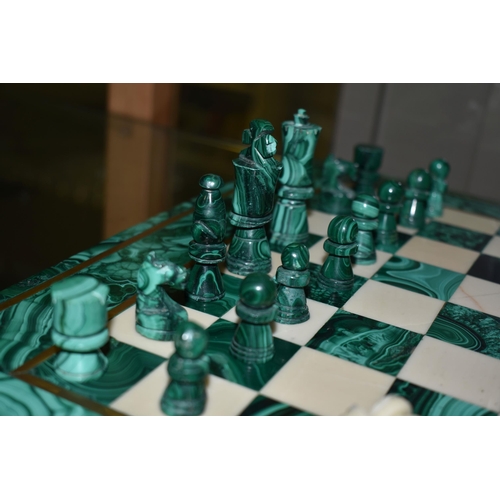 561 - A MALACHITE AND HARDSTONE CHESS SET, the 37cm square board inlaid with brass stringing, height of ki... 