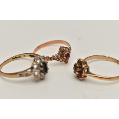 23 - THREE YELLOW METAL RINGS, the first a garnet cluster ring, stamped gold, ring size O, a sapphire and... 