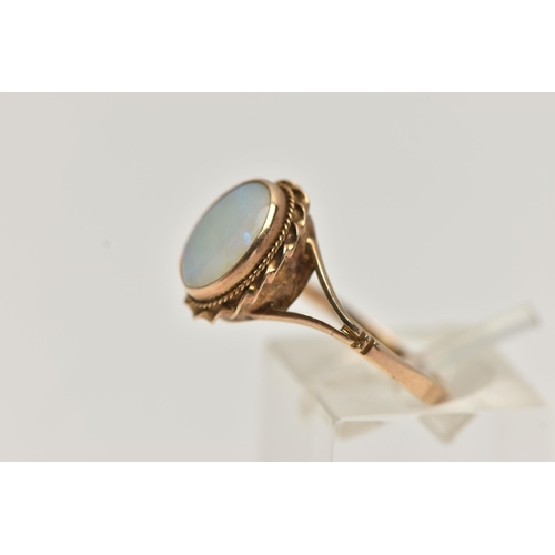 66 - A 9CT GOLD OPAL RING, oval cut opal cabochon, collet set with a fine rope twist surround, bifurcated... 