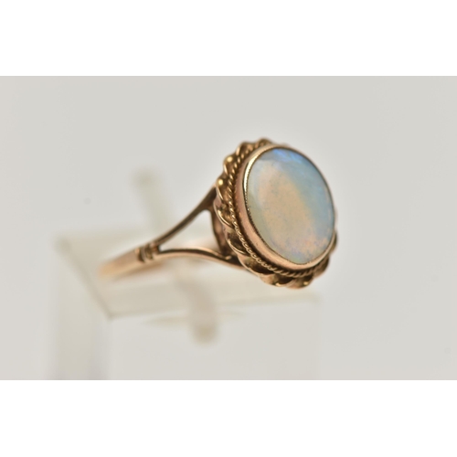 66 - A 9CT GOLD OPAL RING, oval cut opal cabochon, collet set with a fine rope twist surround, bifurcated... 