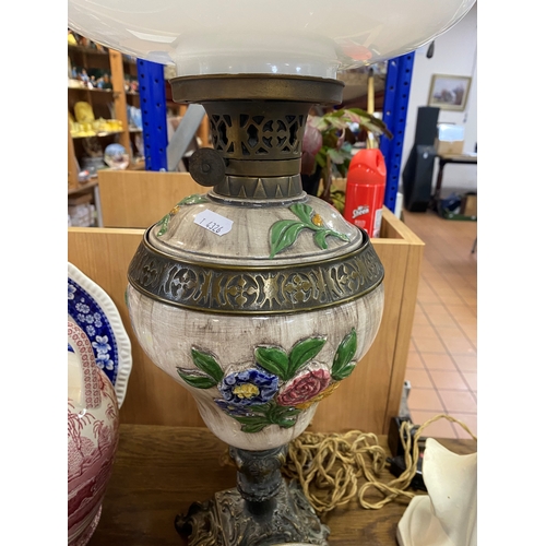 466 - AN OIL LAMP, square brass base with a ceramic reservoir decorated with applied flowers, white glass ... 