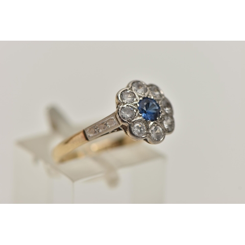 173 - A YELLOW AND WHITE METAL CLUSTER RING, flower shape cluster set with a central circular cut sapphire... 