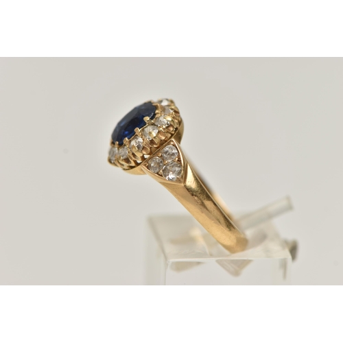 174 - A YELLOW METAL SAPPHIRE AND DIAMOND CLUSTER RING, centring on a cushion cut blue sapphire, measuring... 