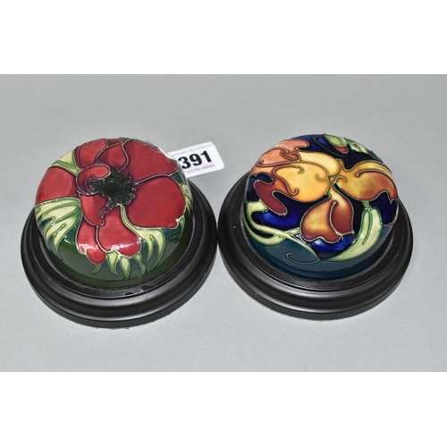 391 - TWO MOORCROFT POTTERY PAPERWEIGHTS, set in wooden plinths, tube lined in Anemone and Miss Alice patt... 