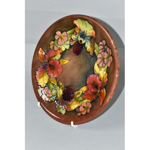 423 - A MOORCROFT POTTERY ORCHID AND SPRING FLOWERS PATTERN PLATE, tube lined with red, pink, purple and y... 