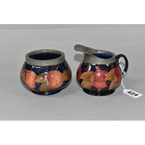 424 - A MOORCROFT POTTERY POMEGRANATE PATTERN CREAM JUG AND SUGAR BOWL, tube lined with fruit on a dark bl... 