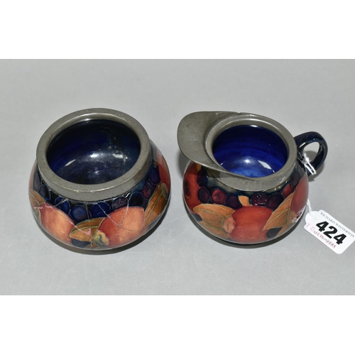 424 - A MOORCROFT POTTERY POMEGRANATE PATTERN CREAM JUG AND SUGAR BOWL, tube lined with fruit on a dark bl... 