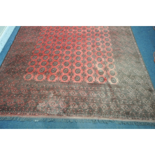 1214 - A LARGE WOOLLEN TEKKE RUG, with a central red field and multi strap boarder, 340cm x 255cm (conditio... 