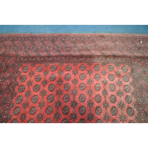 1214 - A LARGE WOOLLEN TEKKE RUG, with a central red field and multi strap boarder, 340cm x 255cm (conditio... 