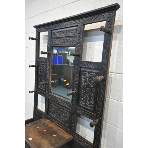 1215 - AN EARLY 20TH CENTURY CARVED OAK HALLSTAND, with ten hooks flanking a bevelled edge mirror, single d... 