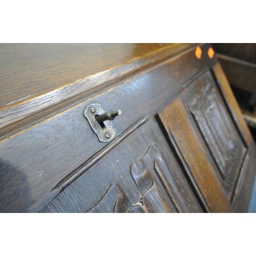 1280 - A 20TH CENTURY OAK LINENFOLD BUREAU, the fall front door enclosing a fitted interior, above four dra... 