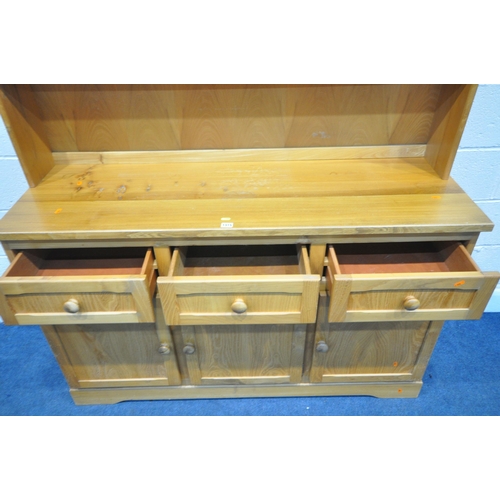 1315 - A MODERN PINE DRESSER, the top with two tier plate rack, the base with three drawers and cupboard do... 